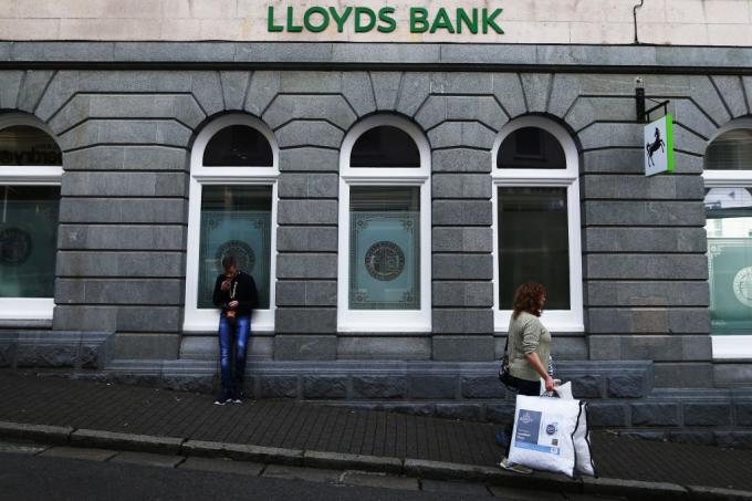 女性はイギリス銀行、ガーンジーの島のLloyds銀行を過ぎて、歩く